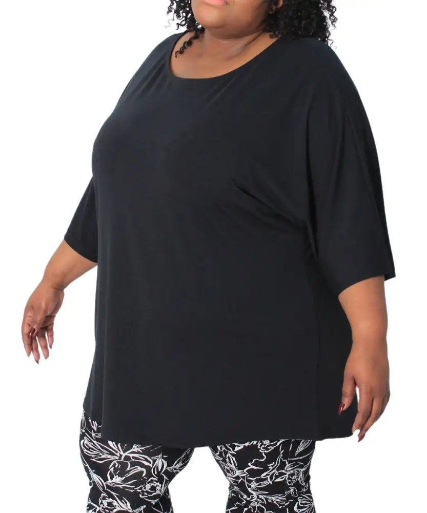 Plus-size woman modeling a Ladies Plain Batwing Top with patterned leggings